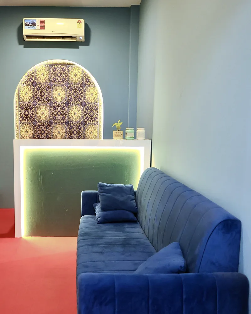 Reception lounge at Artham Luxury Spa in Andheri West, with a blue velvet sofa beside the lit reception desk